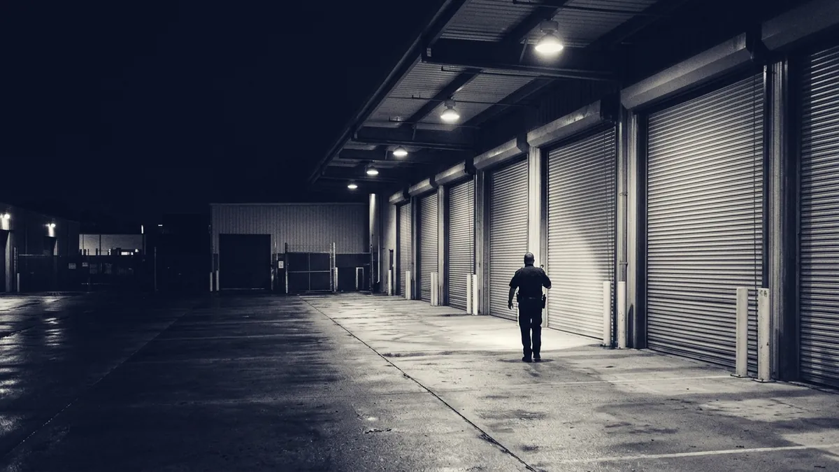 A guard walking a lit loading dock on night patrol