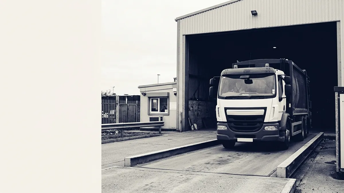 A refuse truck on a weighbridge at a transfer station gate